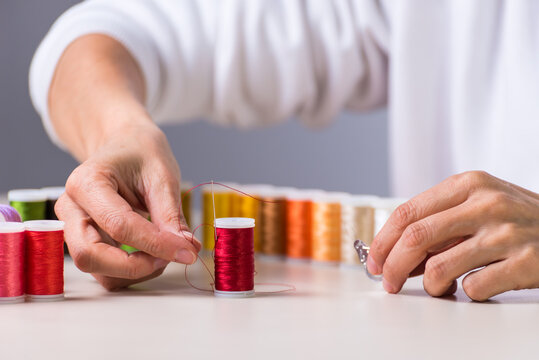 red chilo hands with a needle, dressmaker, atelier, sewing, sewing clothes, embroidering a fabric, selective focus