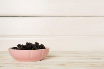 Bowls with mulberry fruit on wooden table