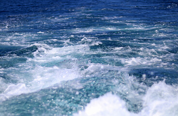 Trail of water and bubbles behind a boat, at sea