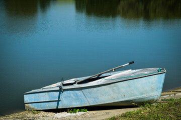 Metal boat on the shore of the pond, clear water
