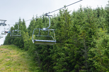 Chairlift chairs going in highland. Huge tourist complex located among forestry hills