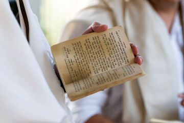 A man holds a siddur or Jewish prayer book during morning services in a synagogue in Israel.