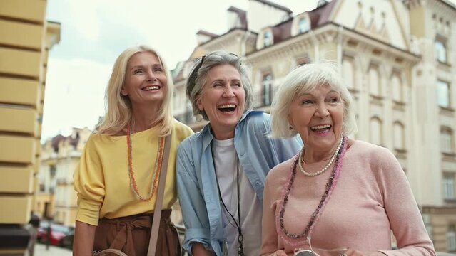 Senior women making shopping in the city center and having fun speaking about gossip and funny things. Concept about seniority and lifestyle
