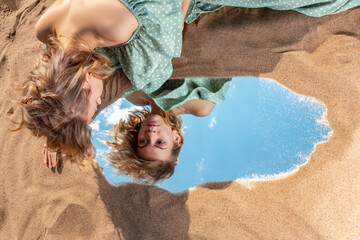 A girl on a sandy beach looks at her reflection in the mirror.