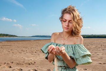 The girl holds sand in her palms.