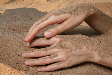 Gentle female hands on the beach sand.