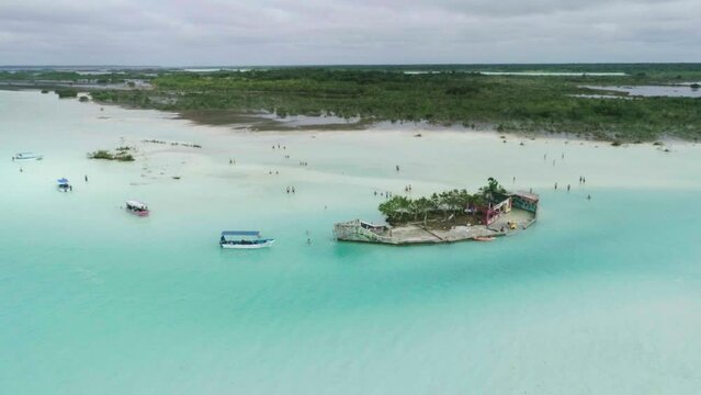 Amazing green island in the middle turquoise milky ocean water with boats around..