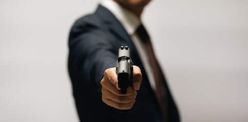 スーツ姿で拳銃を構える男性