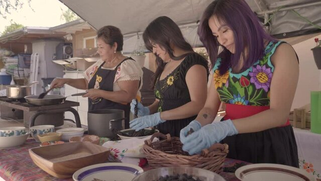 Mom and daughters prepare spices together while they talk and laugh. 