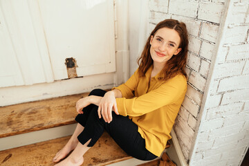 Young woman sitting on wooden stairs looking at camera