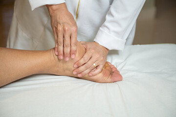 Fototapeta na wymiar Close up em mãos de massagista aplicando massagem terapêutica no pé de um paciente.