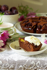 Fototapeta na wymiar Chocolate plum cake with whipped cream, served with cocoa. Rustic style.