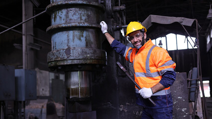 Portrait handsome worker with orange safety suit and yellow helmet  handle wrench work maintenance machine in factory, handsome technician work machine maintenance in machine shop