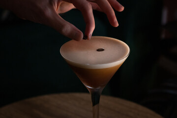 espresso martini cocktail with foam and three coffee beans with hand 