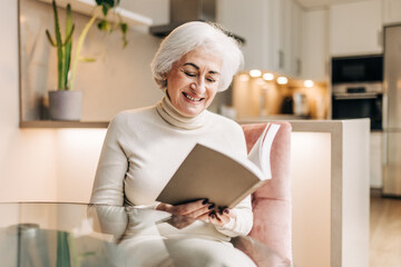 Cheerful senior woman reading a book at home