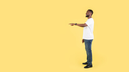 Fototapeta na wymiar African Man Pointing Finger Aside At Empty Space, Yellow Background
