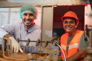Two smiling senior and young engineers working in production line food and beverage factory industry