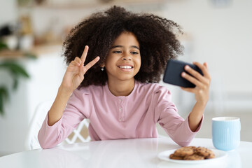 Pretty little black girl taking selfie, using smartphone
