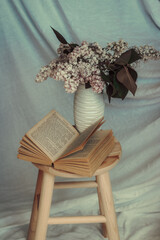 still life with lilac flowers fresh blooming on a valentine's day in a vase and book