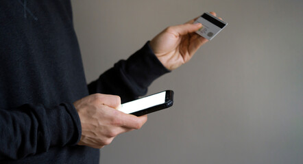 Man holds bank card and mobile phone in his hands.