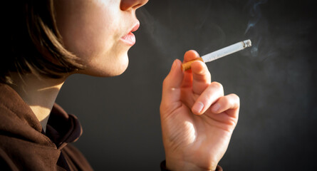 Obraz premium Woman is smoking, holding a cigarette in her hand.