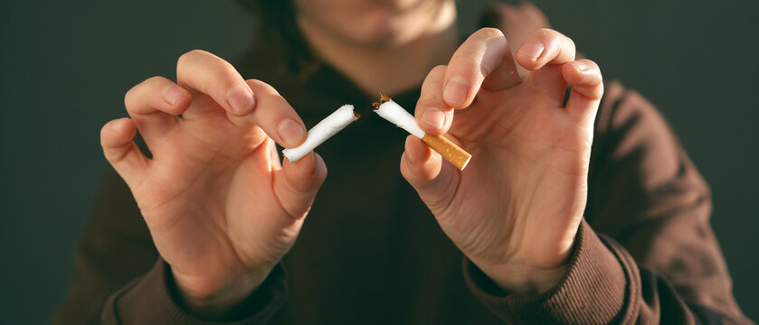 Girl breaks a cigarette in her hands, view closeup.