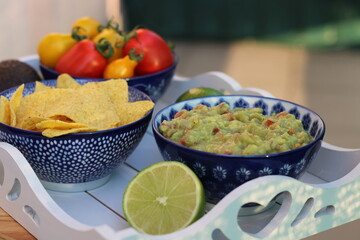 Guacamole home made with tortilla chips ripe red and yellow tomatoes and lime served