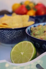 Guacamole home made with tortilla chips ripe red and yellow tomatoes and lime served