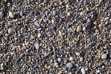 Texture or background of small brown and black stones on the beach forming a very fine sand.