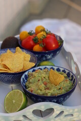 Guacamole home made with tortilla chips ripe red and yellow tomatoes and lime served