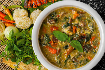 Thai food - spicy curry with ingredients on wooden background