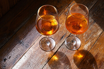 Two glasses of wine or April on a wooden table in a restaurant. Summer rest. Celebrate and enjoy the moment. Tasting of alcoholic beverages. Glass of wine close-up