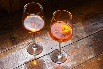 Two glasses of wine or April on a wooden table in a restaurant. Summer rest. Celebrate and enjoy the moment. Tasting of alcoholic beverages. Glass of wine close-up
