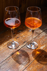 Two glasses of wine or April on a wooden table in a restaurant. Summer rest. Celebrate and enjoy the moment. Tasting of alcoholic beverages. Glass of wine close-up
