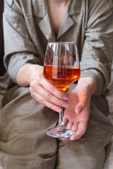A glass of wine, aperol in the hands of a woman resting at home Tasting alcoholic beverages. Romantic evening aperitif. Close-up of a glass of wine. Enjoy the moment