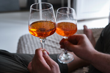 A glass of wine, aperol in the hands of a man resting at home Tasting alcoholic beverages. Romantic evening aperitif. Close-up of a glass of wine. Enjoy the moment
