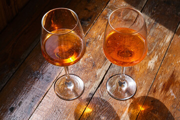 Two glasses of wine or April on a wooden table in a restaurant. Summer rest. Celebrate and enjoy the moment. Tasting of alcoholic beverages. Glass of wine close-up
