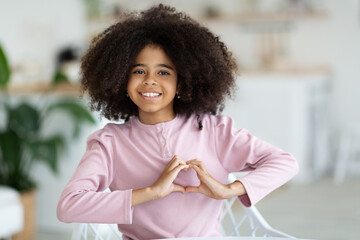 Cute black school girl showing heart symbol next to chest