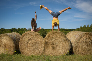 Naklejka na ściany i meble caucasian couple doing stunts on straw bales in France