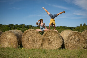 Naklejka na ściany i meble caucasian couple doing stunts on straw bales in France