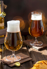 Close-up of two elegant glasses with different types of craft beer on a wooden bar. Natural drink in the pub.