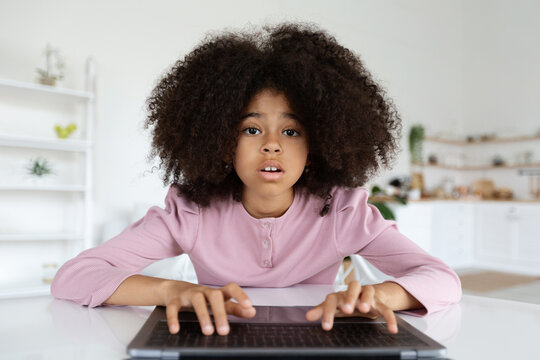 Closeup of cute black preteen girl typing on laptop keyboard