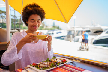Black woman taking photo of food in street restaurant