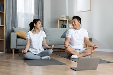 Happy asian family having morning yoga at home, using laptop