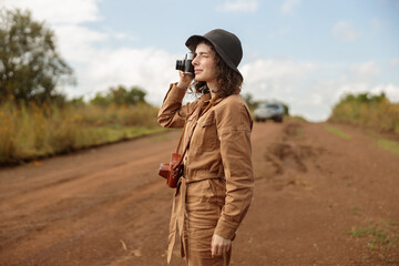 Side view of female traveler taking photo while standing on the road in savannah