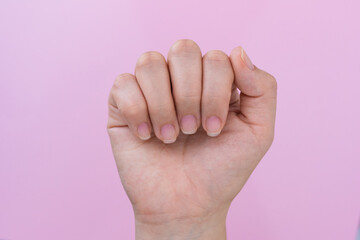 hand of a latin woman showing her nails in a closed hand pose, in the background a pink cardboard,...
