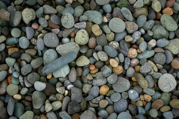 Abstract background texture of random sizes of stones and colored smooth pebbles on the seashore