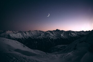 View of the snowy mountains and the moon at night