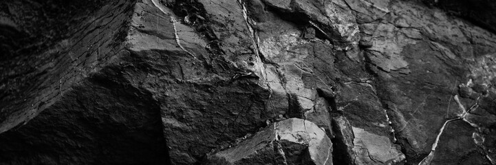 Black white rock texture. Rough mountain surface with cracks. Close-up. Stone basalt background for design. Banner. Wide. Long. Panoramic.