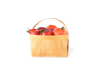 Fresh red and striped tomatoes in straw basket on white isolated background. The concept of farm products or harvest holiday.